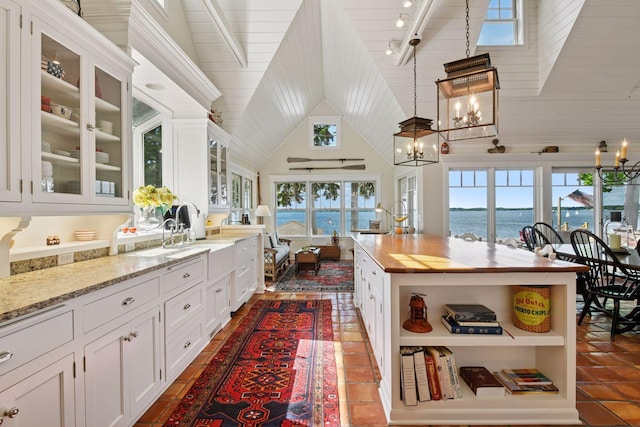 19820 Lakeview Ave, Deephaven, MN 55331 - kitchen with open shelves, white cabinetry, a chandelier, a water view, and high vaulted ceiling