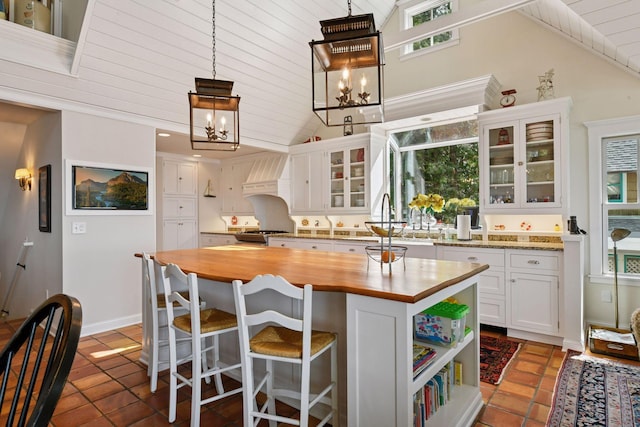 19820 Lakeview Ave, Deephaven, MN 55331 - kitchen featuring wood counters, lofted ceiling, white cabinetry, a kitchen island, and plenty of natural light