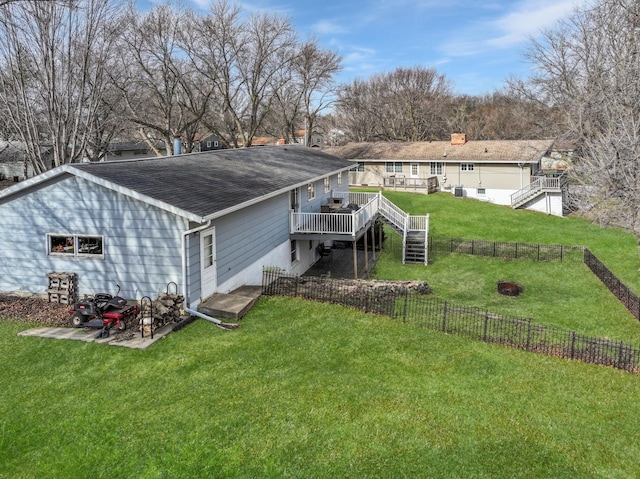 back of property featuring a deck, a fenced backyard, a shingled roof, a lawn, and stairway