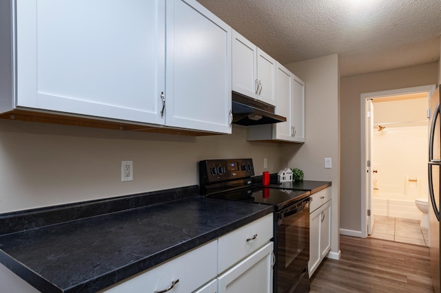 2930 Blaisdell Ave Unit 124, Minneapolis, MN 55408 - kitchen with black range with electric stovetop, under cabinet range hood, white cabinets, dark wood-style flooring, and dark countertops