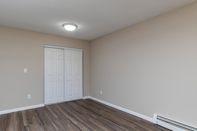 2930 Blaisdell Ave Unit 124, Minneapolis, MN 55408 - unfurnished bedroom featuring baseboard heating, dark wood-type flooring, baseboards, and a textured ceiling