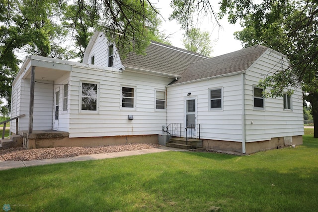 exterior space with roof with shingles and a front lawn