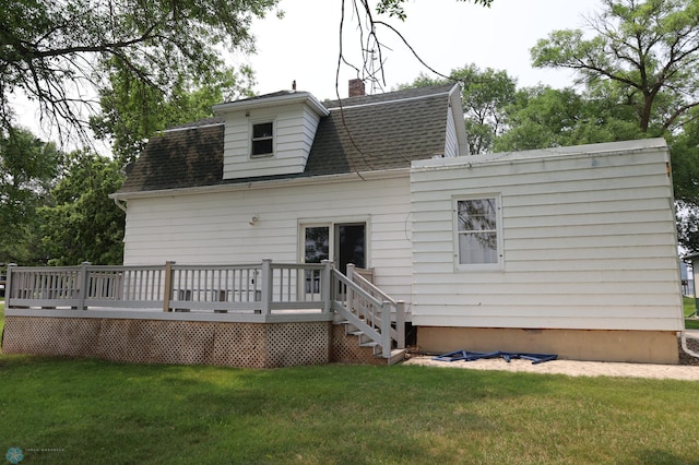 back of house featuring a yard, a chimney, a deck, and roof with shingles