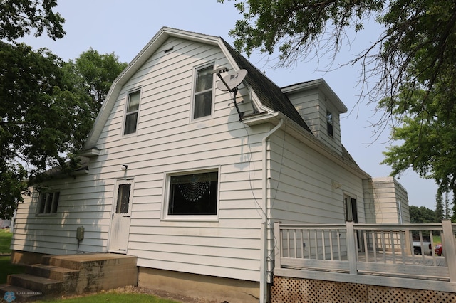 view of side of home featuring a deck and a gambrel roof