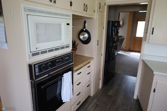kitchen featuring white cabinets, dark wood-style flooring, light countertops, white microwave, and black oven