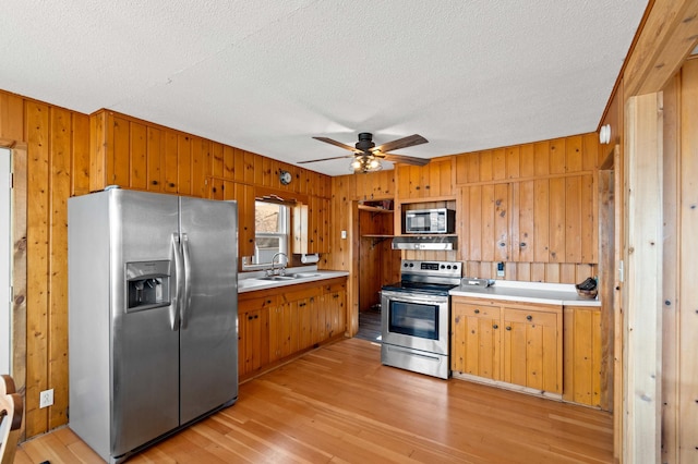 12742 Lake Miltona Dr NE, Miltona, MN 56354 - kitchen with appliances with stainless steel finishes, wood walls, light countertops, light wood-type flooring, and ceiling fan