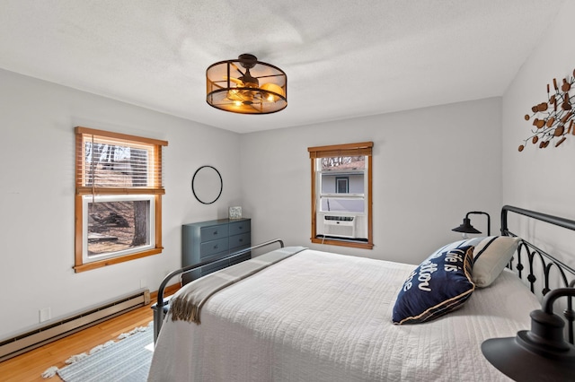 12742 Lake Miltona Dr NE, Miltona, MN 56354 - bedroom with a baseboard heating unit, multiple windows, wood finished floors, and cooling unit