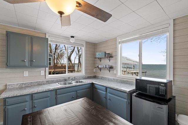 12742 Lake Miltona Dr NE, Miltona, MN 56354 - kitchen with a sink, black microwave, wood walls, open shelves, and fridge