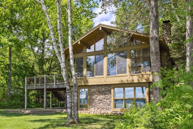 12037 Northgate Ln, Crosslake, MN 56442 - rear view of property with stone siding, a wooden deck, a chimney, a sunroom, and a lawn