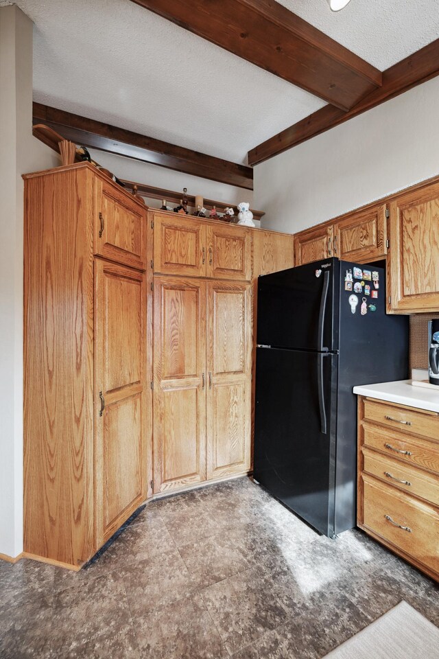 12037 Northgate Ln, Crosslake, MN 56442 - kitchen featuring beam ceiling, freestanding refrigerator, and brown cabinetry