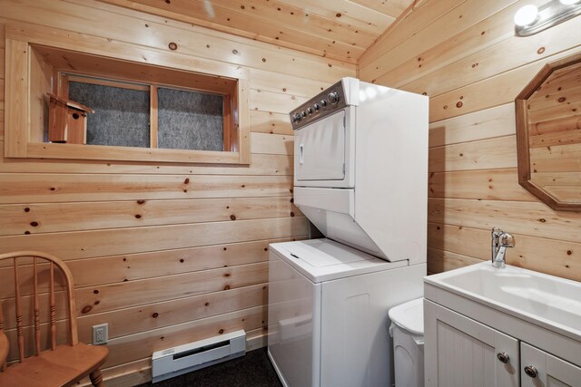 12037 Northgate Ln, Crosslake, MN 56442 - laundry room with stacked washer / drying machine, wooden walls, a baseboard heating unit, and a sink