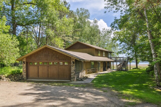12037 Northgate Ln, Crosslake, MN 56442 - view of front facade featuring stone siding, dirt driveway, an attached garage, and a front yard