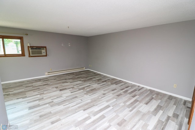 1219 7th St S Unit 1, Moorhead, MN 56560 - spare room with a baseboard heating unit, a wall unit AC, light wood-style floors, and baseboards