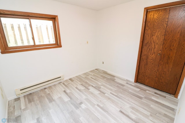 1219 7th St S Unit 1, Moorhead, MN 56560 - unfurnished bedroom featuring baseboard heating, light wood-type flooring, baseboards, and a closet