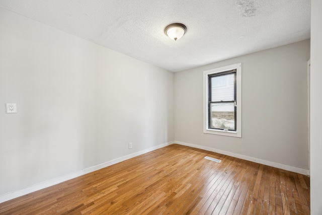 spare room with hardwood / wood-style flooring, baseboards, and a textured ceiling