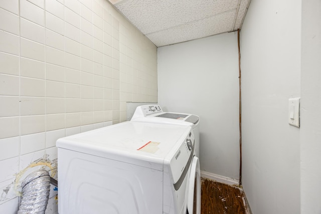 laundry area featuring tile walls, laundry area, dark wood-style flooring, and washer and clothes dryer