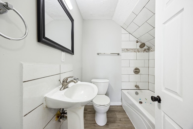full bath with a textured ceiling, toilet, lofted ceiling, wood finished floors, and shower / tub combination
