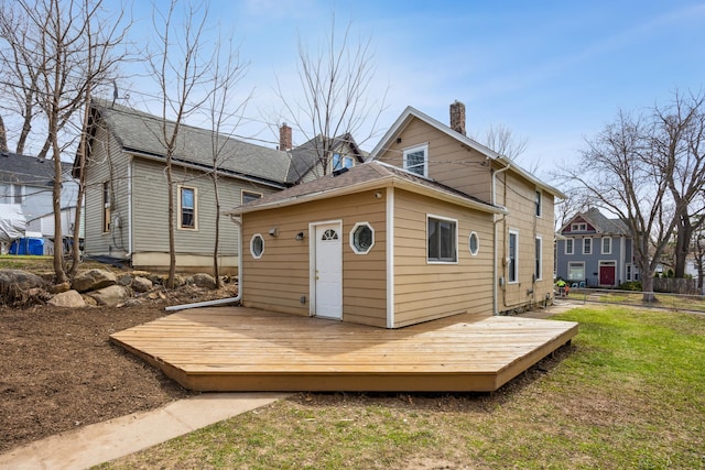 rear view of property with a lawn, a chimney, and a deck