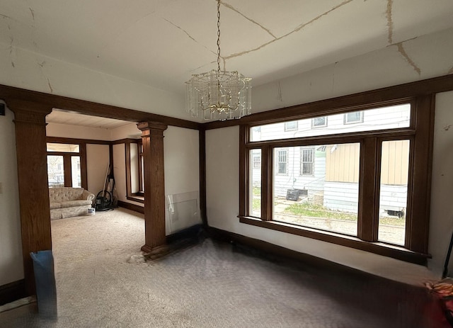 616 5th St, Madison, MN 56256 - empty room featuring carpet flooring, a notable chandelier, decorative columns, and baseboards