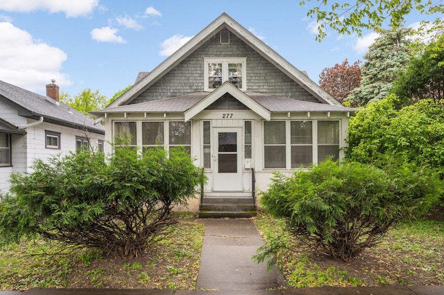 view of front of property with entry steps, a sunroom, and roof with shingles