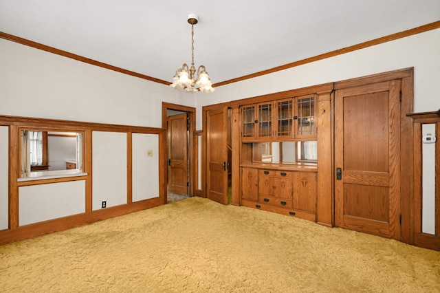 carpeted spare room featuring a chandelier and crown molding