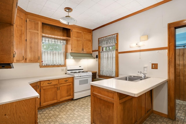kitchen with white gas range, a sink, a peninsula, under cabinet range hood, and light countertops