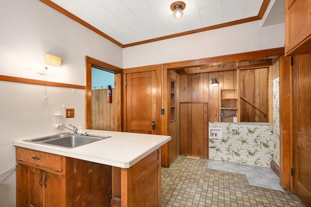 kitchen featuring a sink, brown cabinetry, ornamental molding, and light countertops