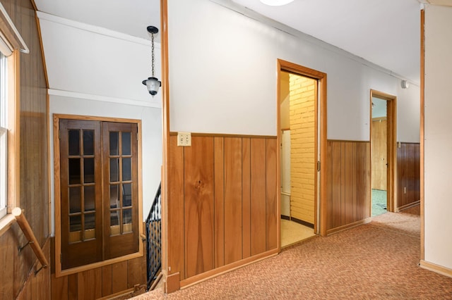 hallway featuring a wainscoted wall, carpet floors, and wooden walls