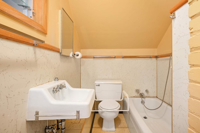 full bath with a sink, toilet, vaulted ceiling, and washtub / shower combination