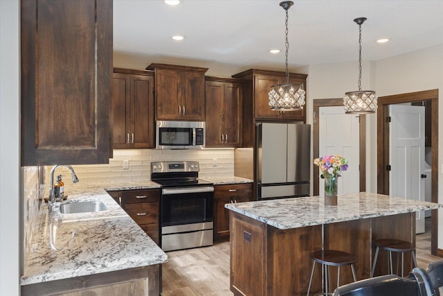 1030 Bellaire Blvd NW, Isanti, MN 55040 - kitchen with stainless steel appliances, a sink, a kitchen island, dark brown cabinetry, and backsplash