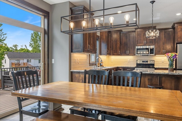 1030 Bellaire Blvd NW, Isanti, MN 55040 - kitchen featuring appliances with stainless steel finishes, dark brown cabinets, a sink, light stone countertops, and recessed lighting