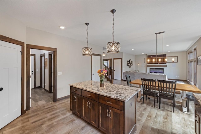 1030 Bellaire Blvd NW, Isanti, MN 55040 - kitchen with a glass covered fireplace, light wood-type flooring, dark brown cabinets, baseboards, and recessed lighting