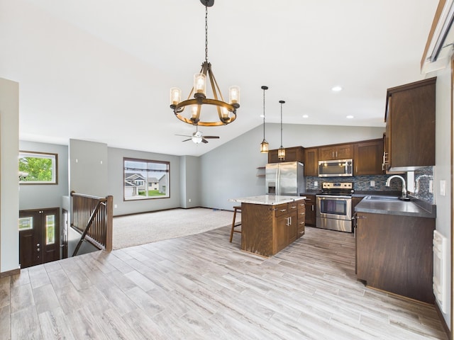 1214 Olivia St SE, New Prague, MN 56071 - kitchen featuring appliances with stainless steel finishes, a chandelier, a sink, lofted ceiling, and a kitchen breakfast bar