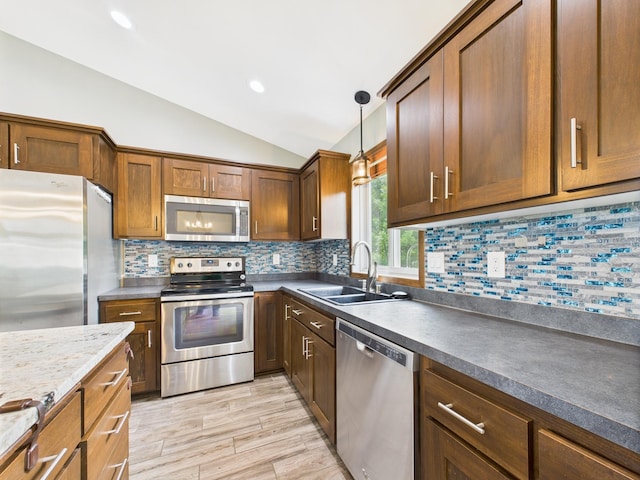 1214 Olivia St SE, New Prague, MN 56071 - kitchen featuring stainless steel appliances, a sink, vaulted ceiling, light wood finished floors, and hanging light fixtures