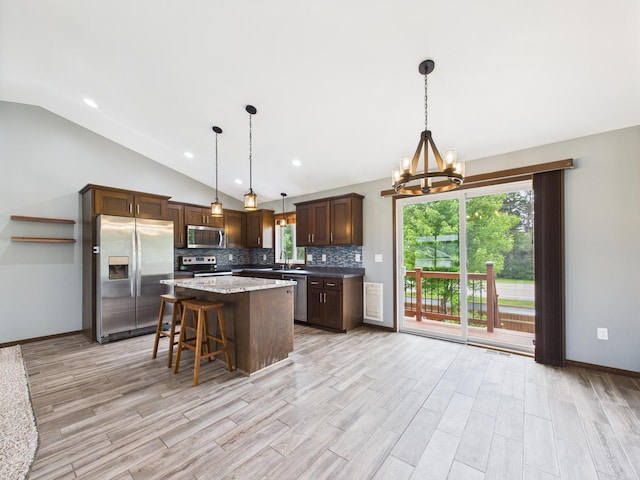 1214 Olivia St SE, New Prague, MN 56071 - kitchen featuring appliances with stainless steel finishes, vaulted ceiling, a chandelier, tasteful backsplash, and a center island