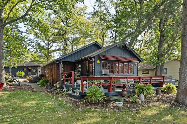 rear view of property with cooling unit, a wooden deck, a lawn, and board and batten siding
