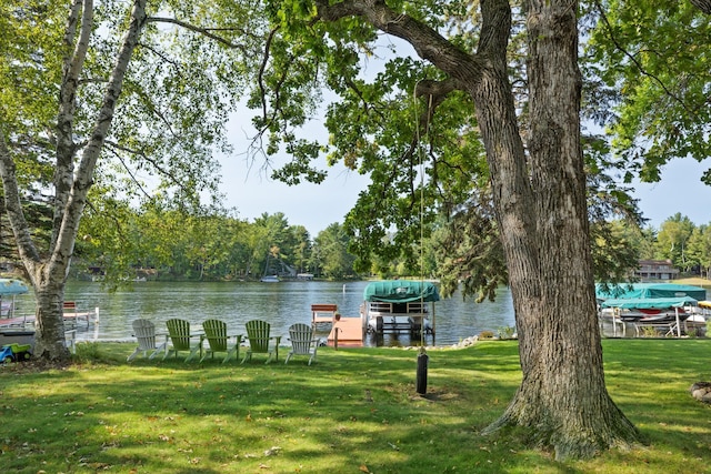 view of dock with a water view and a lawn