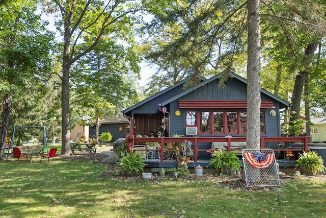rear view of house with board and batten siding, a yard, and a wooden deck