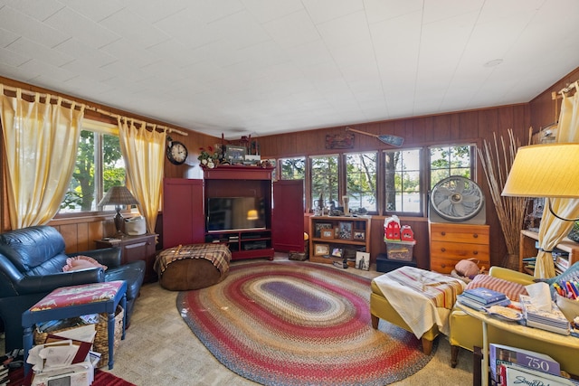 living room featuring wooden walls, carpet floors, and a healthy amount of sunlight