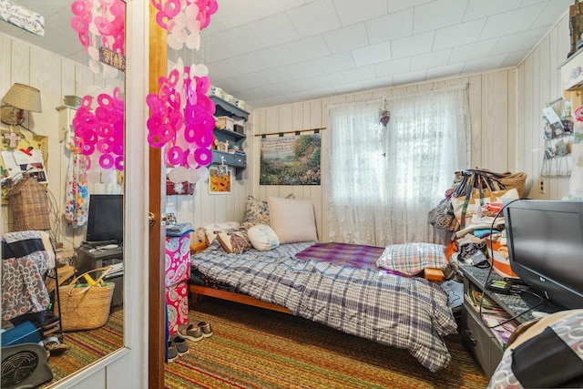bedroom featuring wooden walls and carpet floors