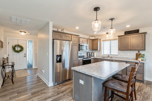 413 Fawn Run, Kenyon, MN 55946 - kitchen featuring appliances with stainless steel finishes, wood finished floors, baseboards, a center island, and a breakfast bar area