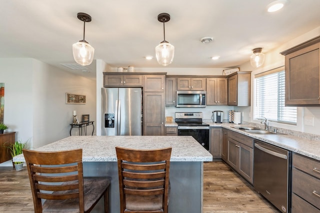 413 Fawn Run, Kenyon, MN 55946 - kitchen with appliances with stainless steel finishes, a sink, a kitchen island, light wood finished floors, and pendant lighting