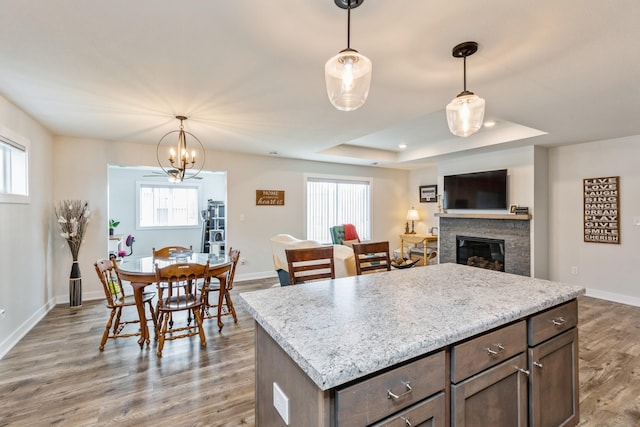413 Fawn Run, Kenyon, MN 55946 - kitchen featuring a raised ceiling, light wood-type flooring, a stone fireplace, baseboards, and decorative light fixtures