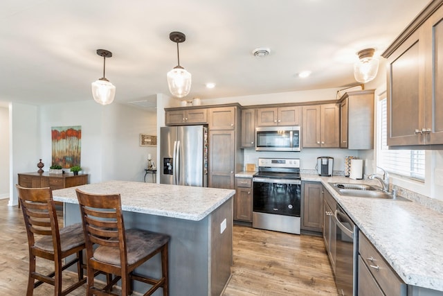 413 Fawn Run, Kenyon, MN 55946 - kitchen featuring appliances with stainless steel finishes, a sink, a kitchen island, a breakfast bar area, and light wood finished floors