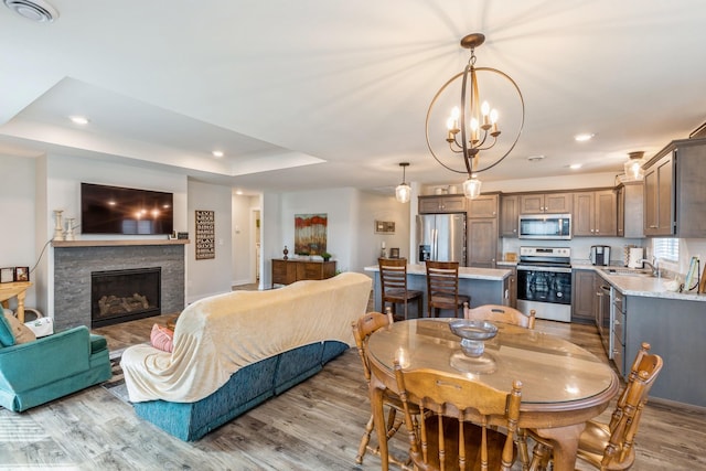 413 Fawn Run, Kenyon, MN 55946 - dining area with light wood finished floors, recessed lighting, a stone fireplace, a chandelier, and a raised ceiling