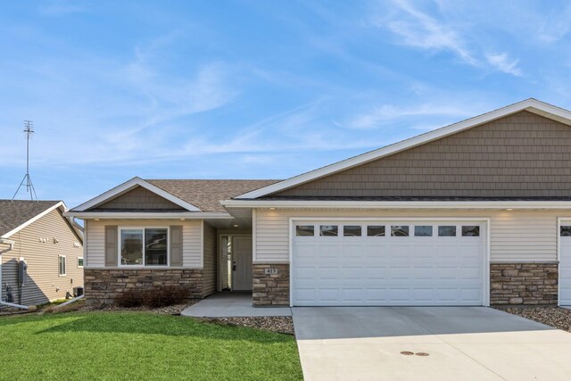 413 Fawn Run, Kenyon, MN 55946 - view of front facade featuring stone siding, driveway, a garage, a front lawn, and roof with shingles