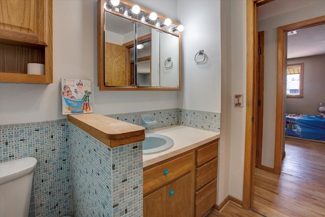 607 Cross Ave S, Amery, WI 54001 - half bath with vanity, a wainscoted wall, toilet, tile walls, and wood finished floors