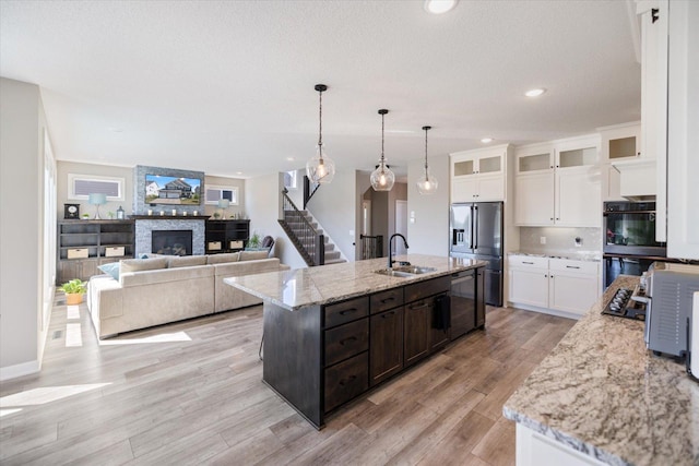 5360 Pine Island Rd, Woodbury, MN 55129 - kitchen featuring appliances with stainless steel finishes, a sink, light wood-type flooring, white cabinets, and an island with sink