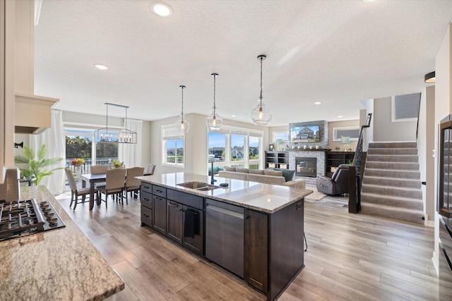 5360 Pine Island Rd, Woodbury, MN 55129 - kitchen with a sink, dark brown cabinetry, a glass covered fireplace, light stone counters, and appliances with stainless steel finishes