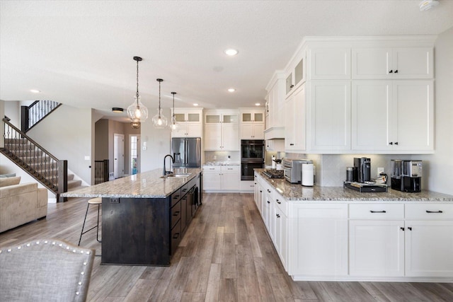 5360 Pine Island Rd, Woodbury, MN 55129 - kitchen with stainless steel fridge with ice dispenser, light wood finished floors, a sink, glass insert cabinets, and a breakfast bar